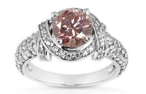 Zlatý prsteň s ružovým diamantom a postrannými bielymi diamantmi.