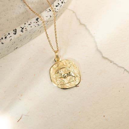 Zlatý prívesok so symbolmi znamenia zverokruhu Kozorožec