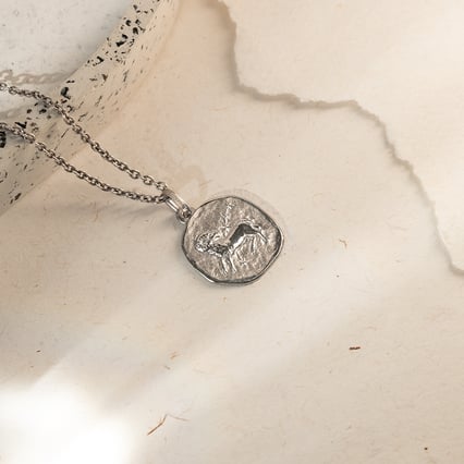 Strieborný prívesok so symbolmi znamenia zverokruhu Kozorožec